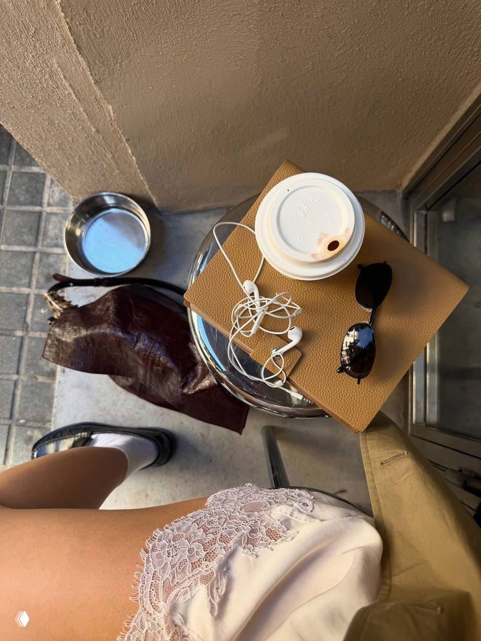 Утренний кадр: бумажный стакан с кофе, блокнот, наушники и солнцезащитные очки на столике у кафе — атмосфера утренних ритуалов