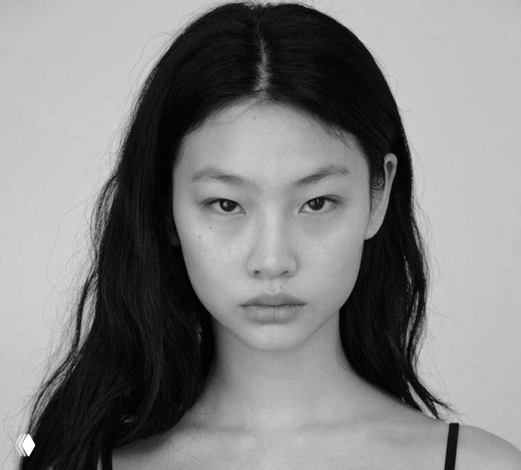 Чёрно‑белое художественное фото женщины крупным планом; выражение лица нейтральное, видна текстура кожи и контуры черт.