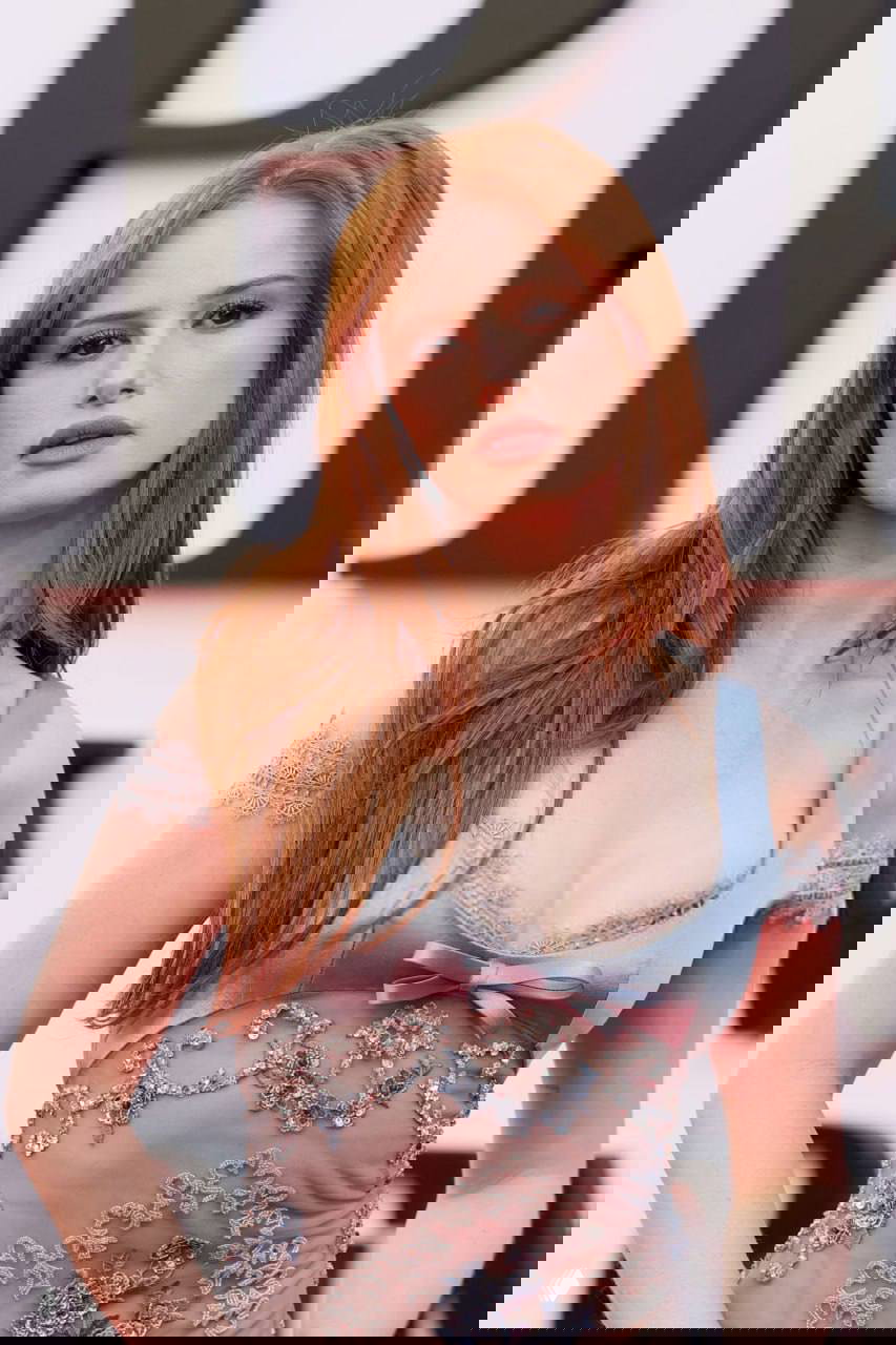 Крупный план женщины на красной дорожке в нежно-голубом вышитом платье, акцент на макияже и деталях наряда