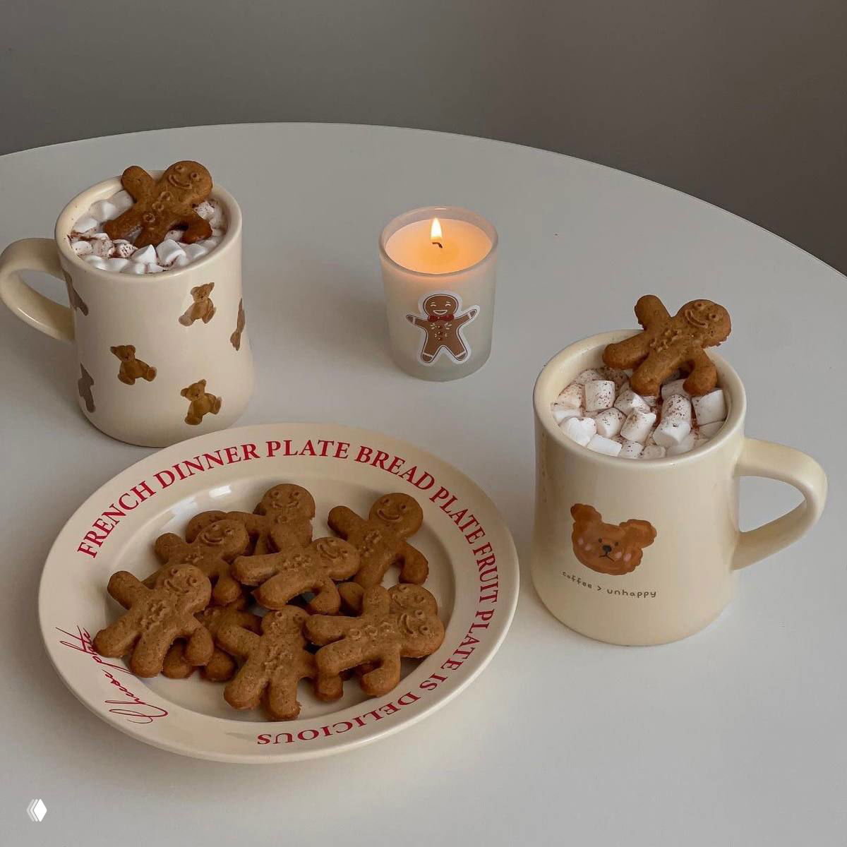 Тарелка и кружки с имбирными человечками и маршмеллоу, свеча и минималистичный праздничный декор на столе; тёплая кофейно‑коричневая гамма кадра.
