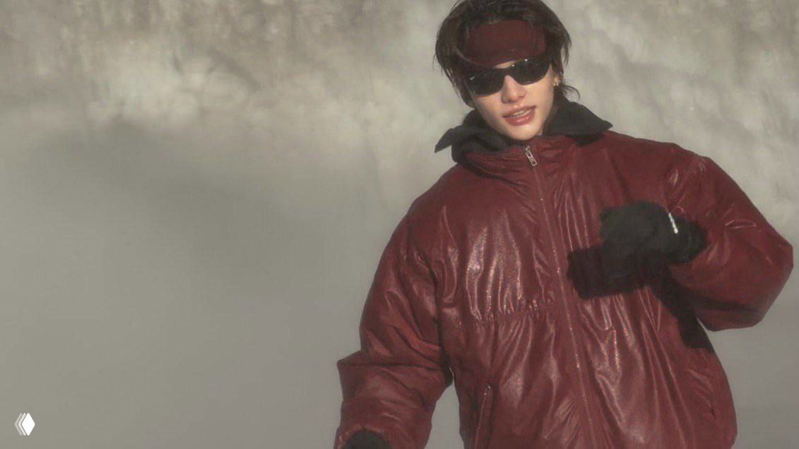 Крупный план человека в тёмно-красной пуховой куртке и солнцезащитных очках на фоне снежного пейзажа — атмосферный портрет из исландской поездки.