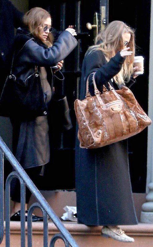 Две женщины в длинных пальто и с большими сумками идут по ступеням; кадр показывает, как длина вещей и обуви влияет на силуэт невысоких девушек.