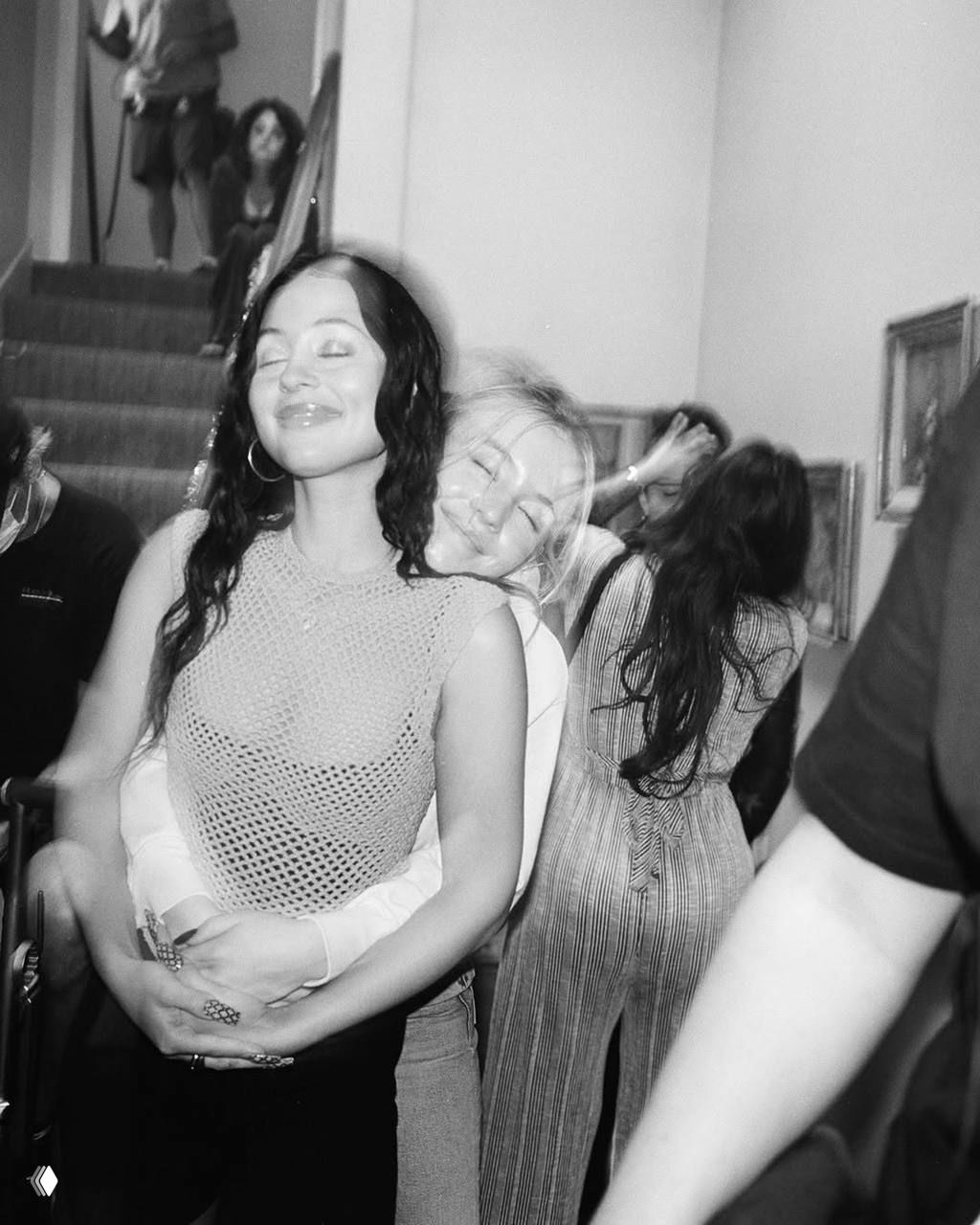 Чёрно-белый тёплый кадр: Барби Феррейра в образе Кэт обнимает коллегу на лестнице — момент поддержки и дружбы на площадке.