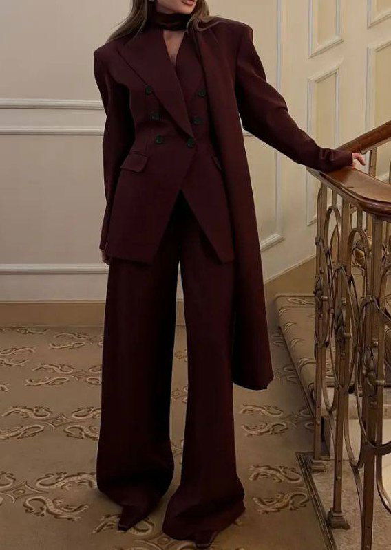 Полный рост женщины в двубортном бордовом костюме и широких брюках на лестнице — сдержанный, статусный и тёплый новогодний аутфит для Козерога.