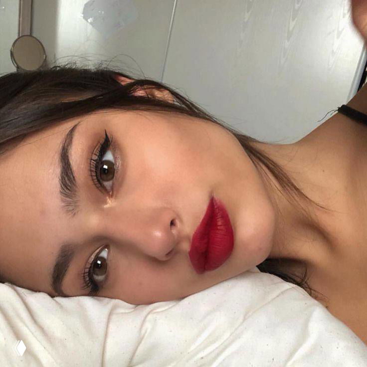 Селфи девушки с яркими матовыми алыми губами и тонкой стрелкой; подчёркнутые брови и аккуратный контур губ.