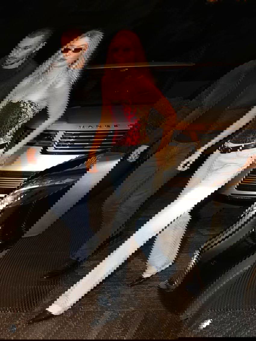 Вечерний выход: женщина в корсетном топе с принтом и светлых джинсах выходит из автомобиля рядом с внедорожником.