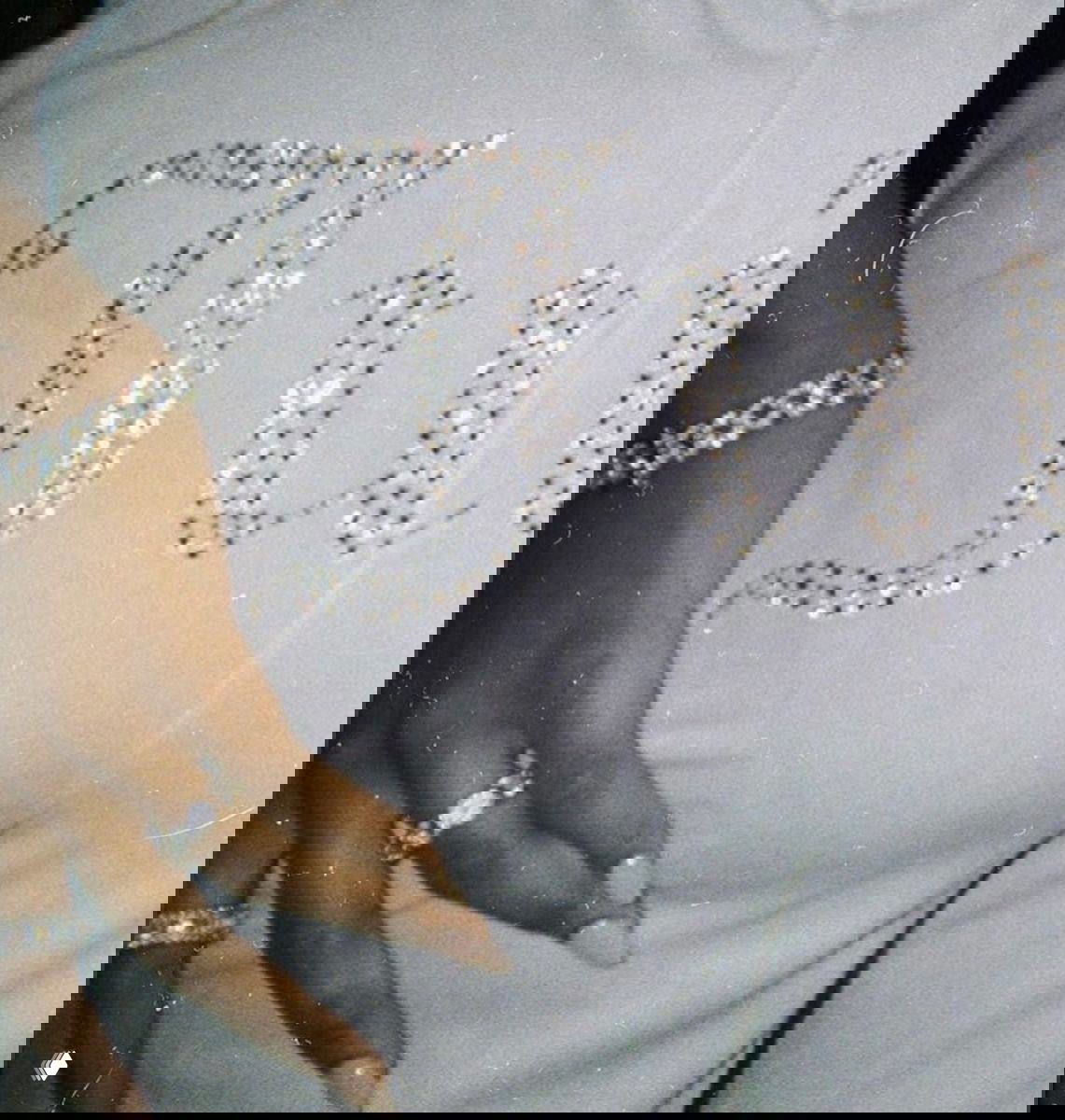 Фрагмент одежды с декоративными кристаллами и рука с бриллиантовыми кольцами; текстура и блеск подчёркивают гламурный стиль образа.