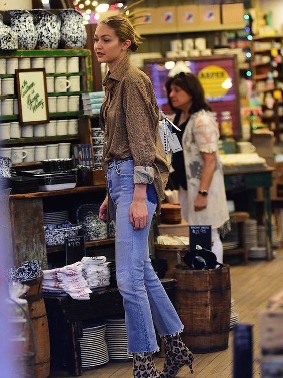 Магазинный кадр: женщина в рваных джинсах и рубашке рассматривает товары в интерьерном магазине, вокруг полки с посудой.