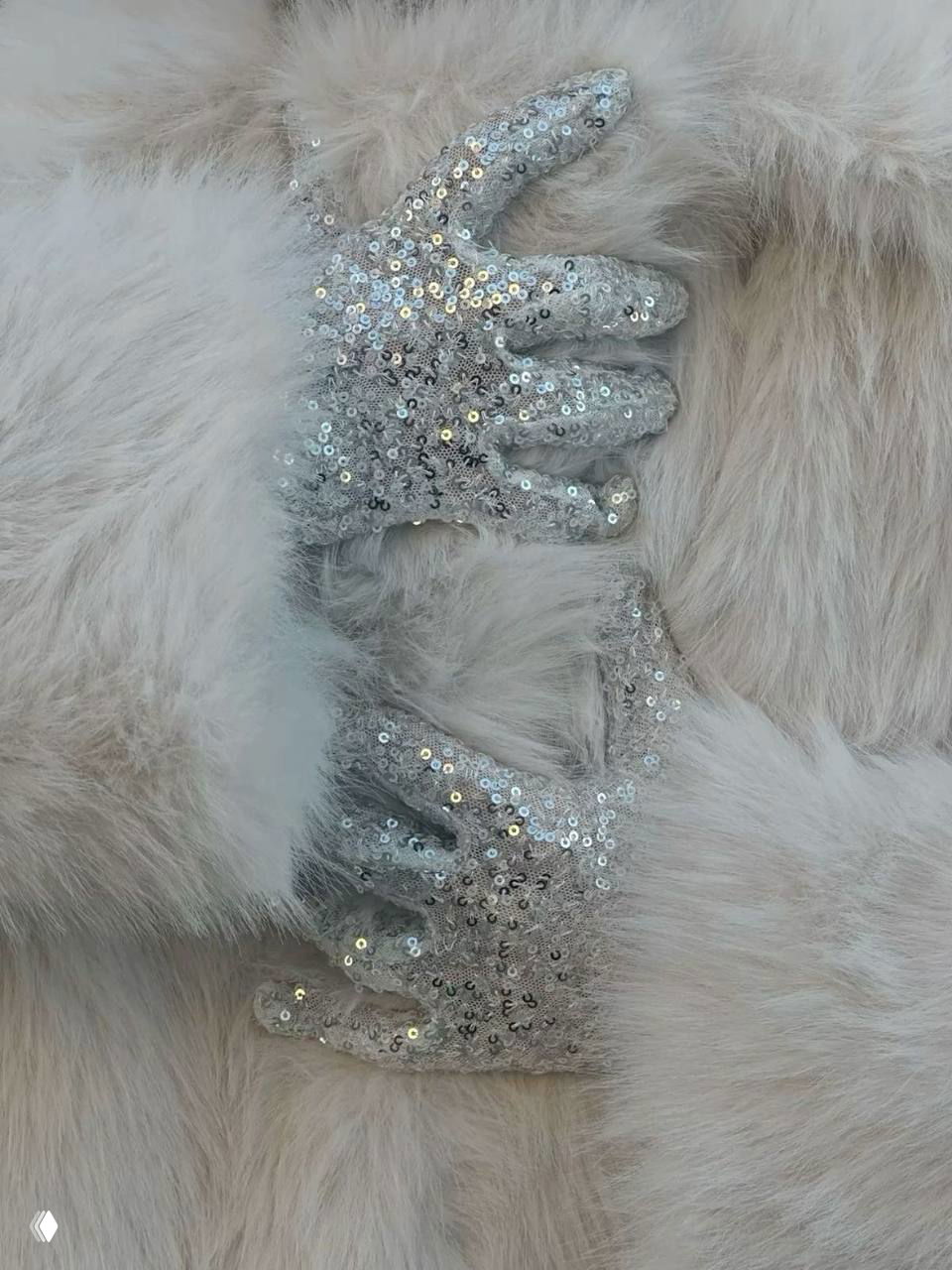 Руки в перчатках с пайетками на мягком меховом фоне; изображение иллюстрирует текстуры и блеск в образе и аксессуарах.