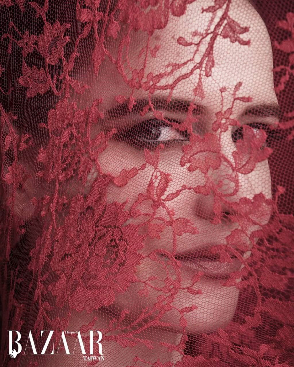 Крупный план лица за красным кружевом: художественный кадр с текстурой материи и игрой света в модной фотосессии.