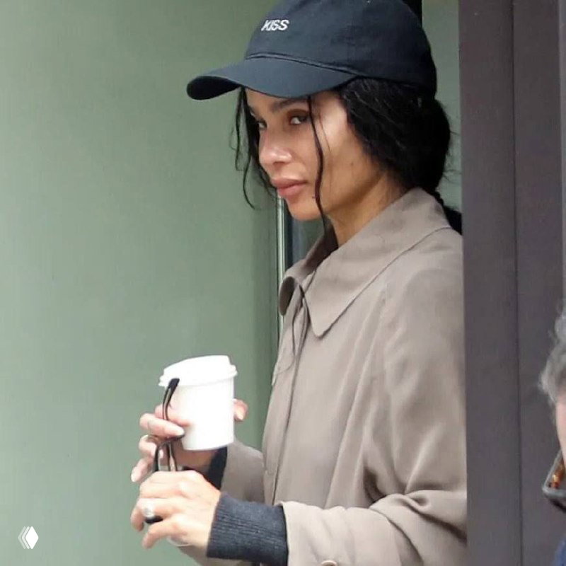 Крупный план женщины в кепке с чашкой в руках; видны лицо и левая рука с аксессуарами и кольцом на пальце.