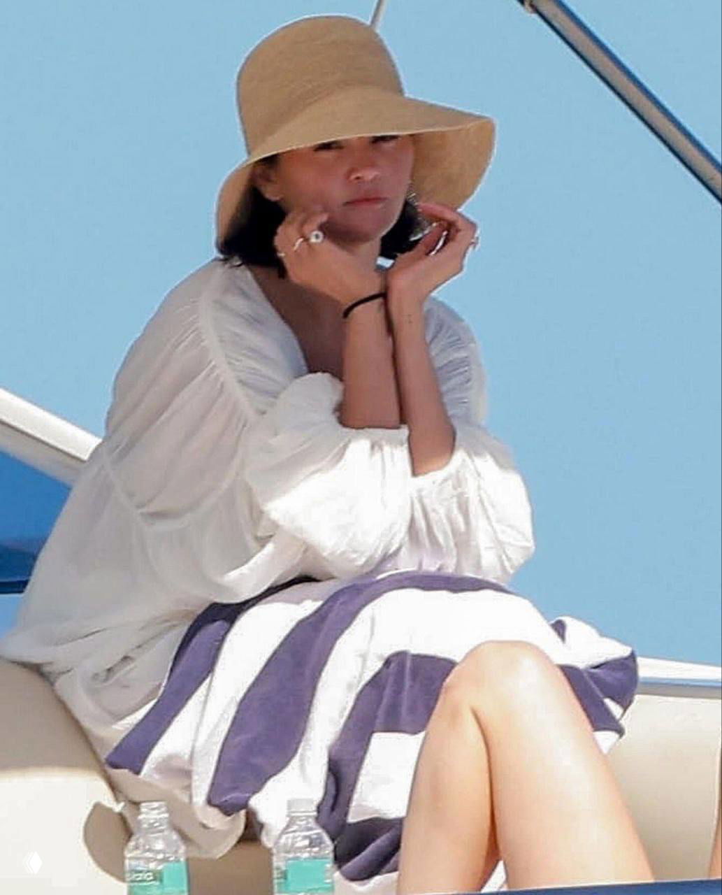 Крупный план Селены Гомес в белой тунике и соломенной шляпе на палубе яхты — лицо и поза певицы видно в расслабленном отдыхе.