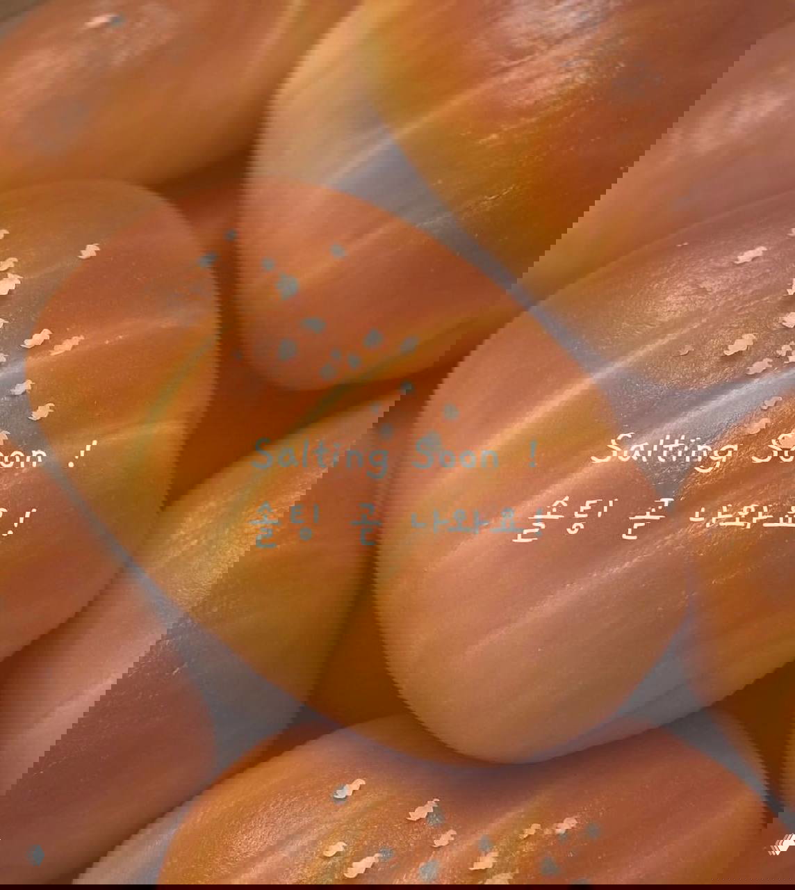 Крупный план подрумяненной корейской булочки с заметными крупинками соли на поверхности, акцент на текстуре корочки и форме.