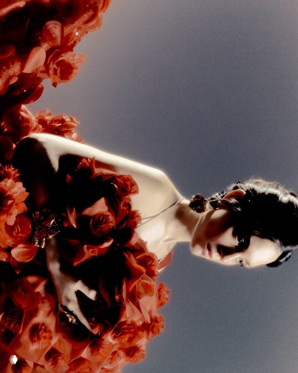 Крупный план красочного текстурного платья с цветочными элементами; студийная съемка под акцентным светом подчеркивает фактуру ткани.