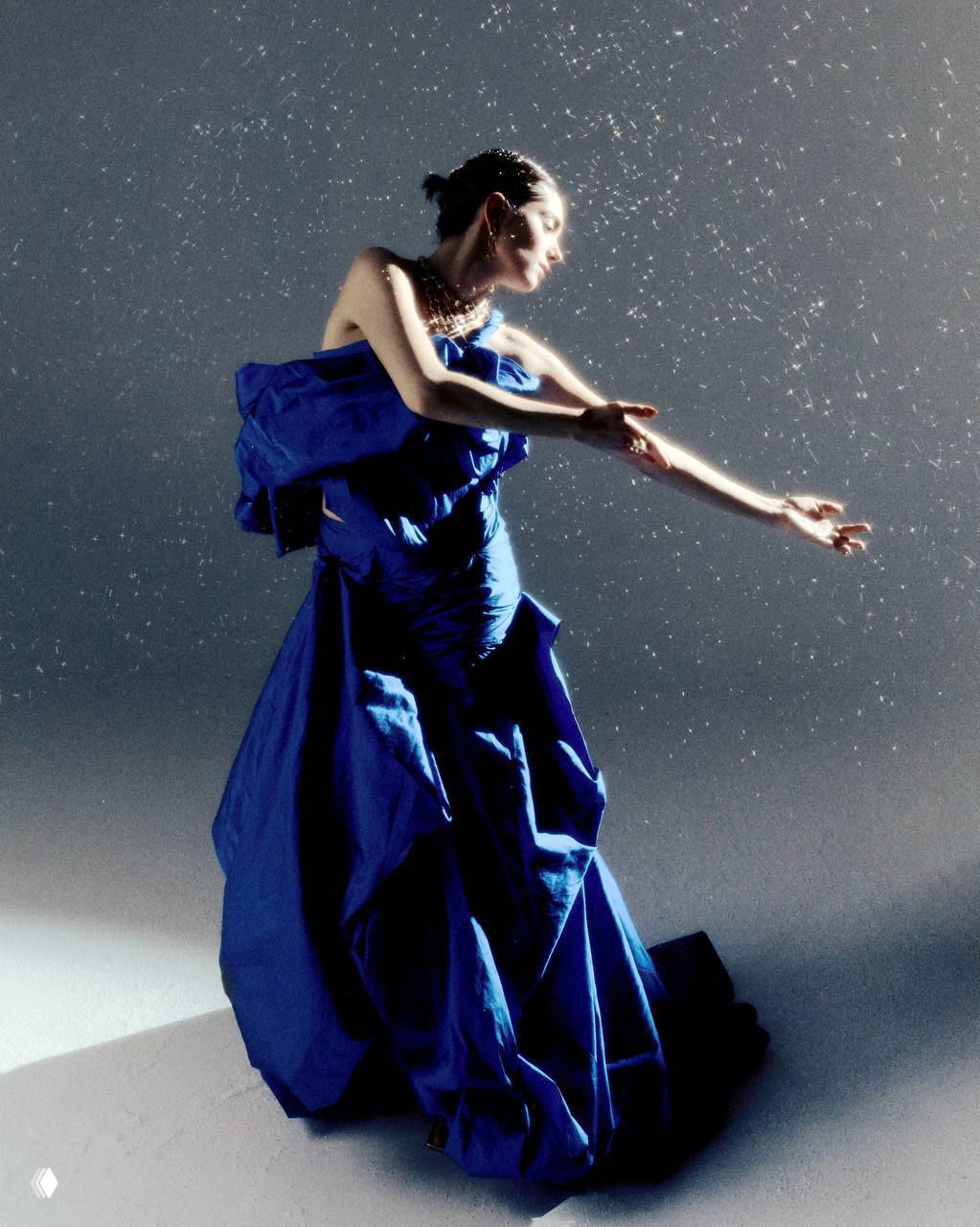 Драматический портрет в красном наряде с боковым светом, глубокие тени и акцент на профиле и текстуре ткани платья в студии.