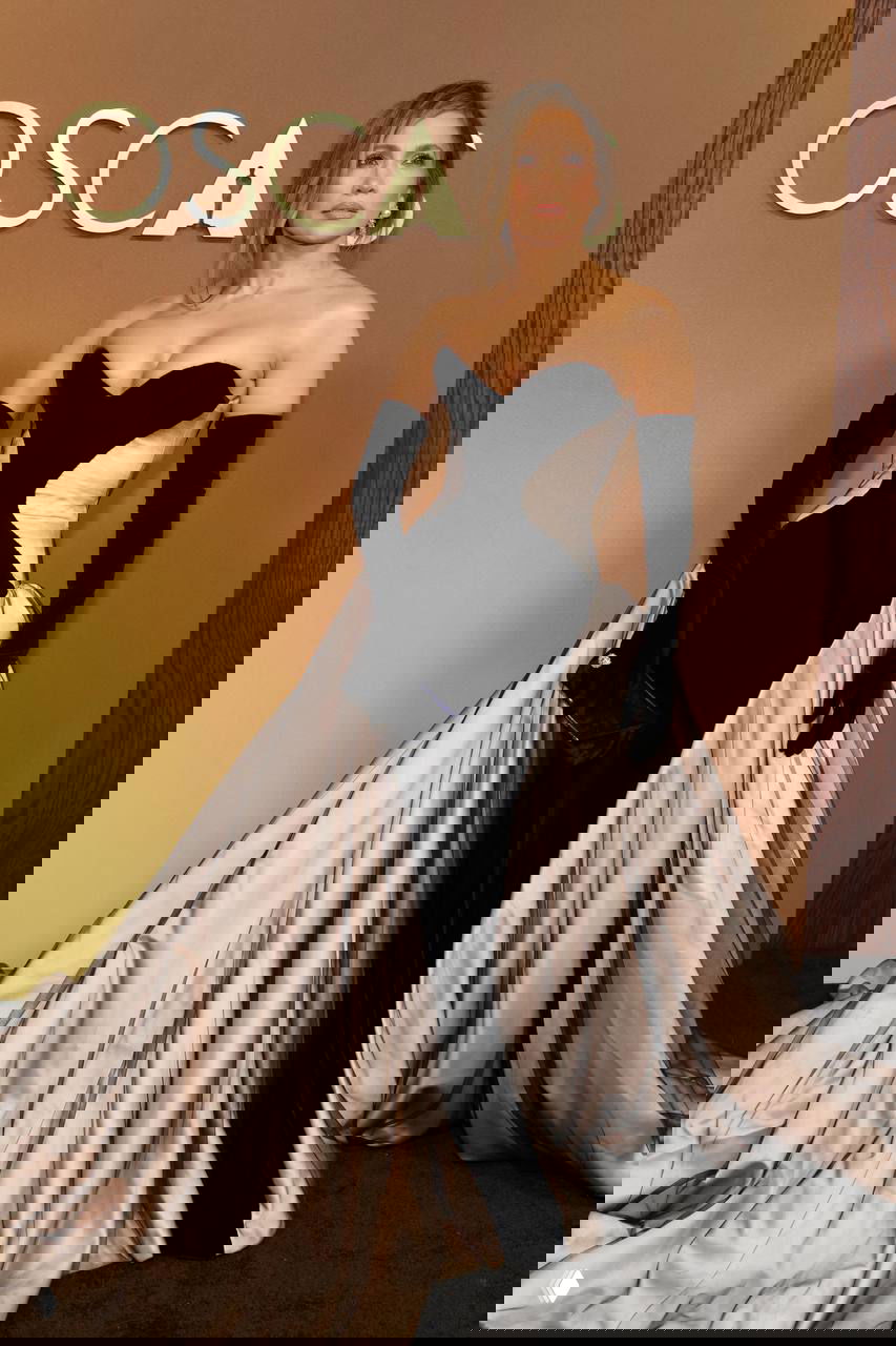 Женщина в чёрно-бежевом вечернем платье с длинными перчатками на красной дорожке Governors Awards, элегантная поза у логотипа мероприятия, фотография с Governors Awards в Лос-Анджелесе.