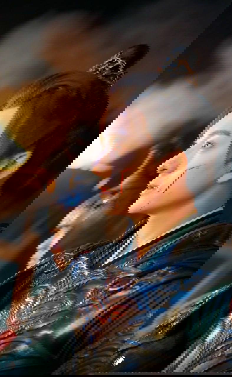 Кадр исторической мини-драмы: мужчина в броне с кровью на щеке на фоне огня и воинов — драматическая военная сцена в вертикальном формате.