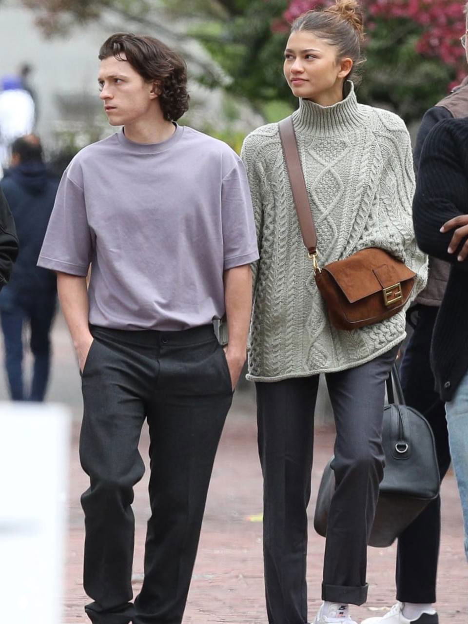 Том Холланд и Зендея идут рядом по городу в повседневной одежде: снимок папарацци, пара выглядит сосредоточенной и спокойной, уличный кадр.