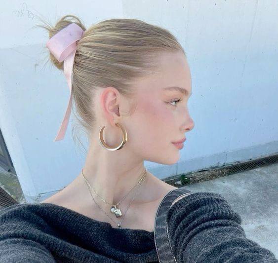 Мини-фото в профиль молодой женщины с высоким хвостом и лёгким макияжем в пастельных оттенках на нейтральном фоне