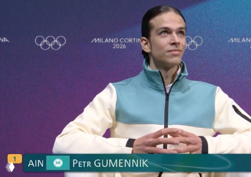 Телевизионный кадр с именем Петра Гуменника; изображение сильно искажено цифровыми артефактами, заметна пикселизация экрана.