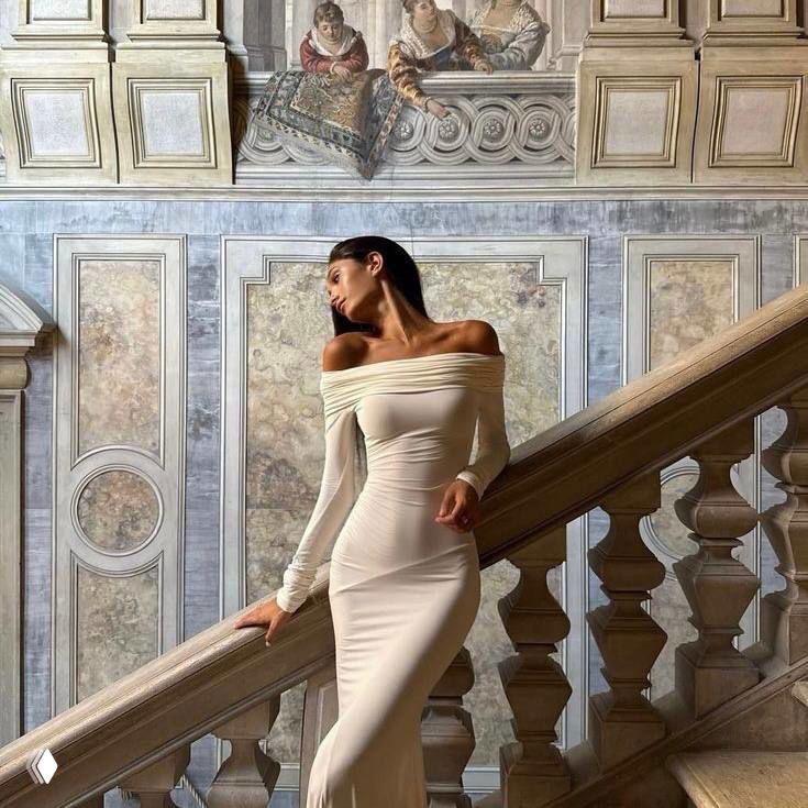 Женщина в элегантном бежевом платье на классической лестнице — минималистичный образ с тонкой эстетикой и праздной вечерней атмосферой.