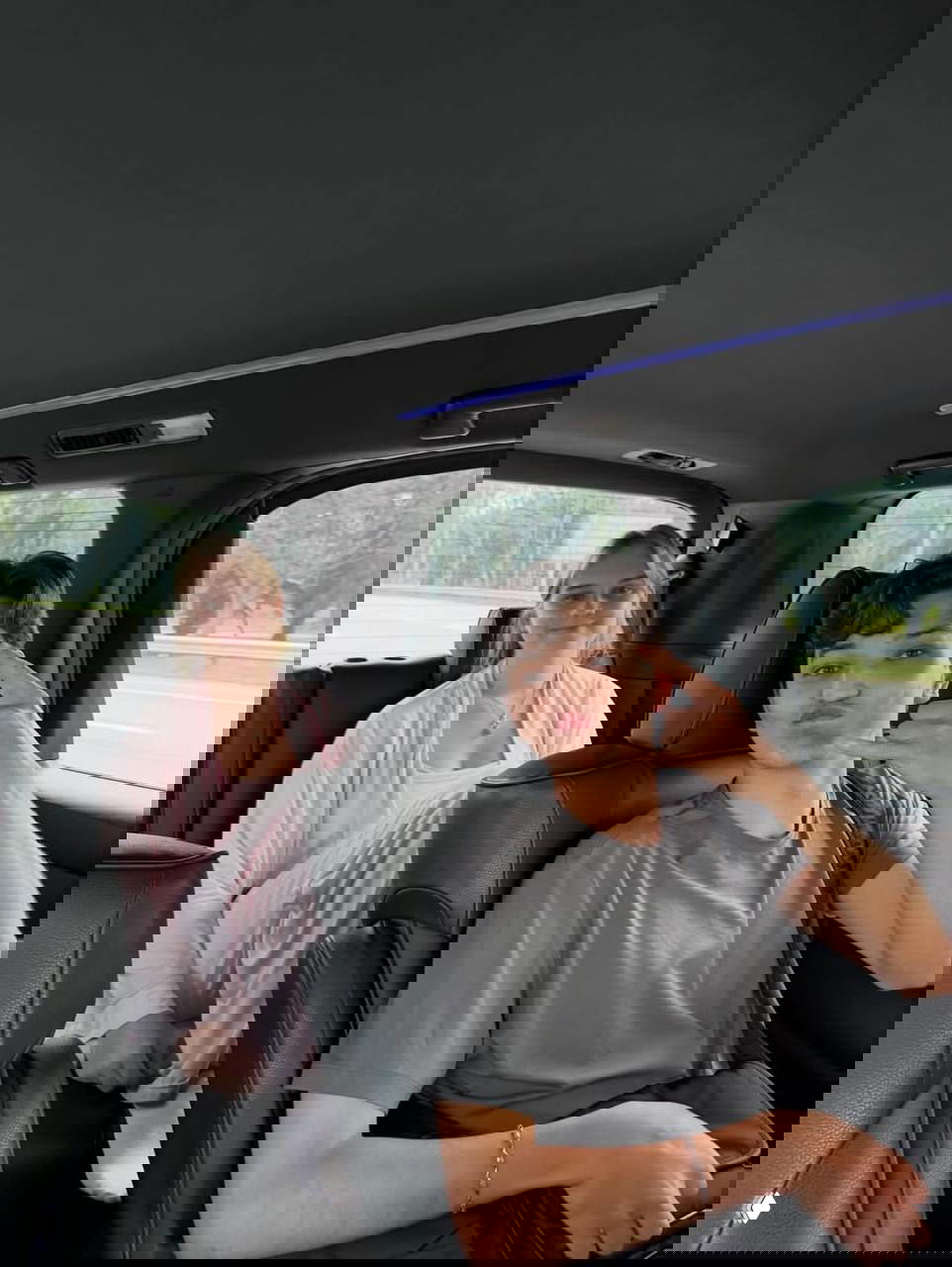 Акмаль и жена в салоне автомобиля: пара сидит на заднем диване в дороге, видно окна и зелёные пейзажи за стеклом.