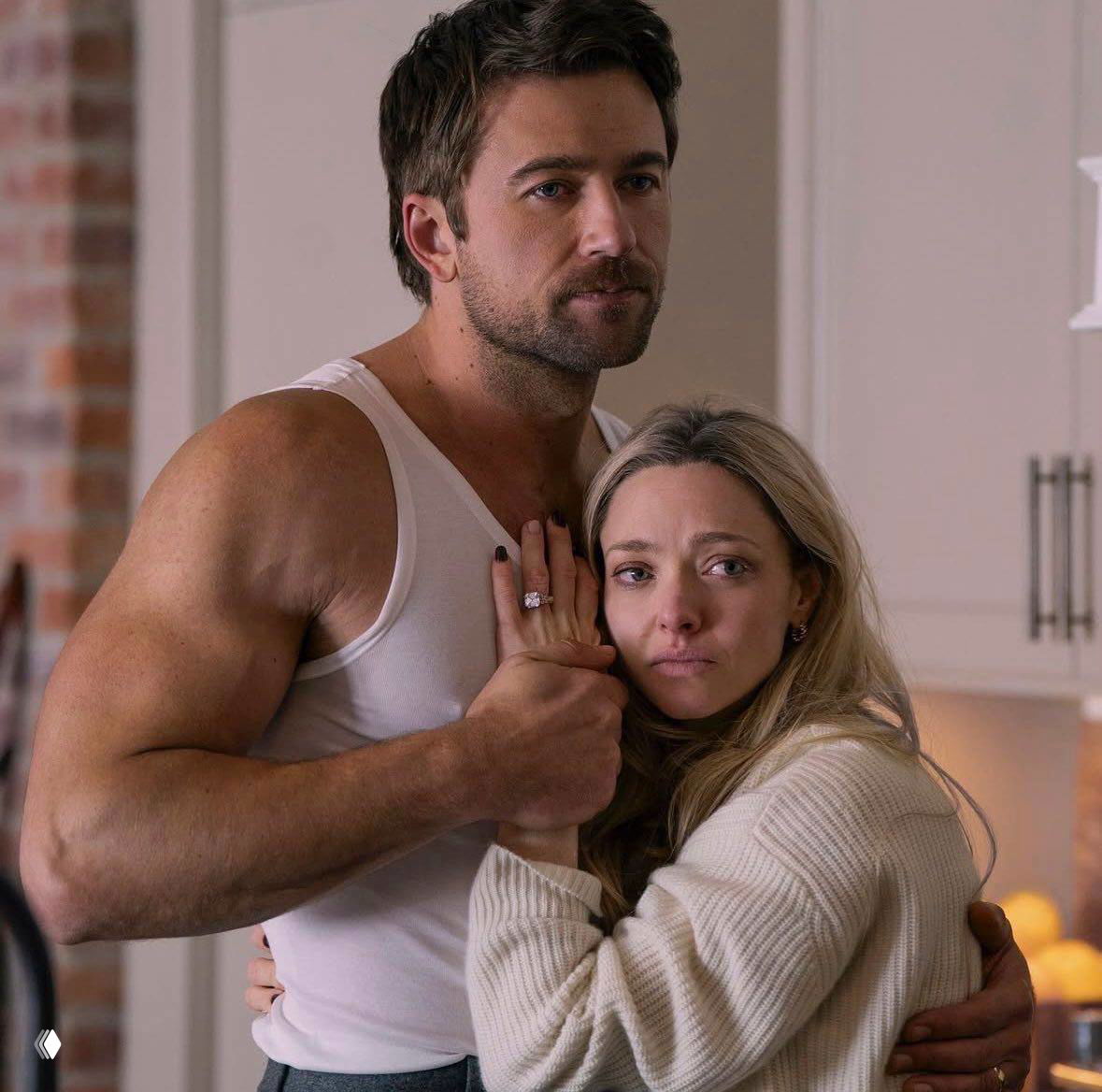 Кадр из фильма: мужчина в майке обнимает женщину в свитере; сцена подчёркивает напряжённую и уязвимую динамику отношений в паре.