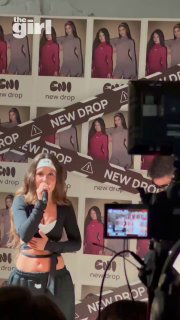 Аля Еникеева поёт и позирует на сцене перед камерами; на заднем плане баннеры ENI с фотографиями коллекции и надписью NEW DROP, съёмочная техника.