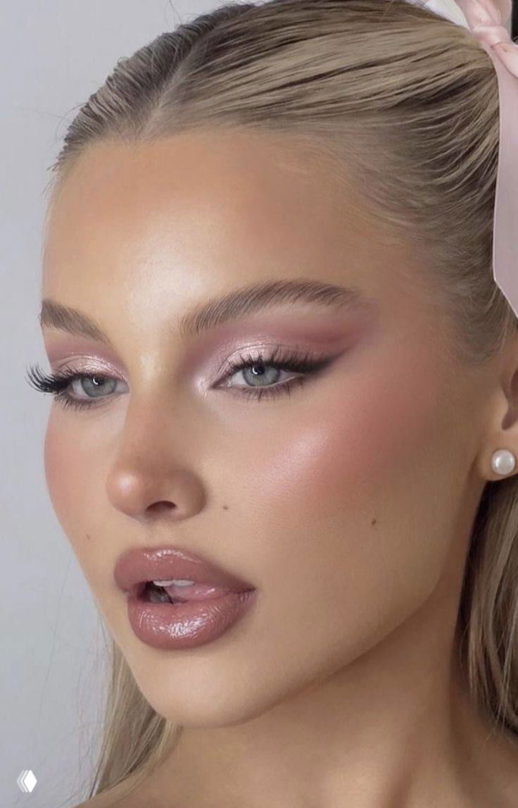 Портрет модели с ровной кожей и розовыми сияющими тенями на веках, подчёркнутыми ресницами и глянцевой помадой — романтичный праздничный лук.