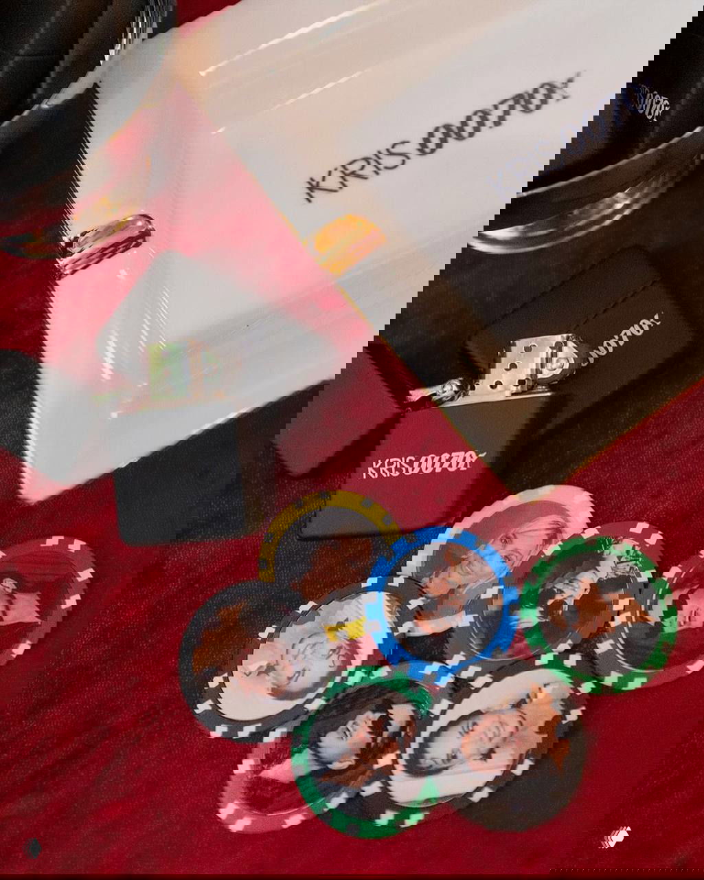 Детали столика с аксессуарами вечеринки: зажигалки и пепельница с надписью KRIS0070 и покерные фишки с мини-фотографиями гостей на бархатной скатерти.