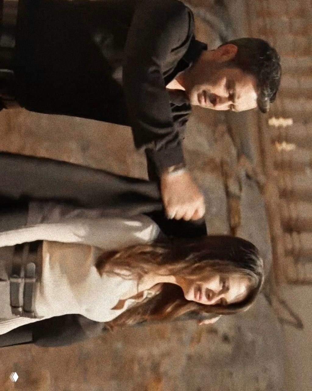 Сцена в интерьере: Джихан держит Алью за руку, оба сосредоточены, приглушённый свет и кирпичные стены на фоне.