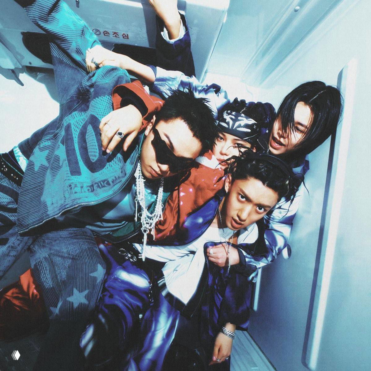 Динамичное промо‑фото k‑pop коллектива: плотная композиция из нескольких участников в сценическом освещении и разноцветных костюмах.