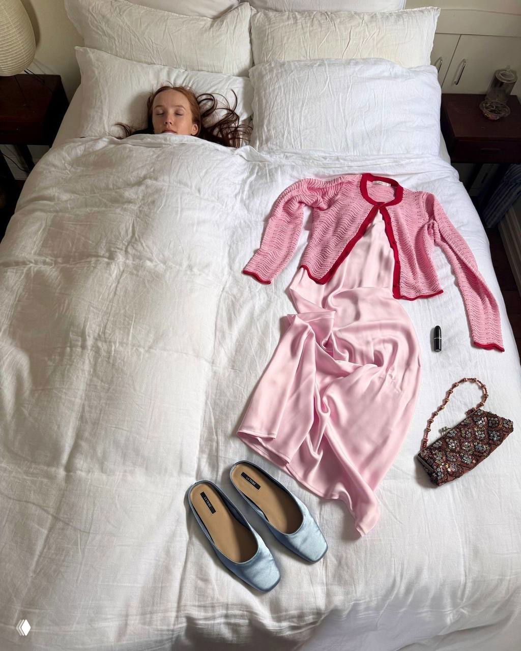 Плоская укладка на кровати: розовое платье и кардиган выложены рядом с туфлями и сумкой — подготовка образа для праздника в спокойной палитре.