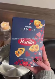 Коробка пасты в форме сердечек Barilla держится над кипящей кастрюлей — упаковка показана крупным планом в кухонной обстановке
