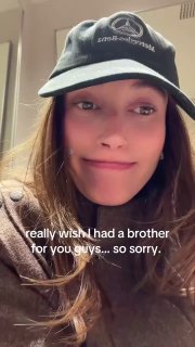 Селфи женщины в чёрной кепке с наложенным английским текстом «really wish I had a brother for you guys...», тёплый тон, реалистичная обработка, домашняя сцена