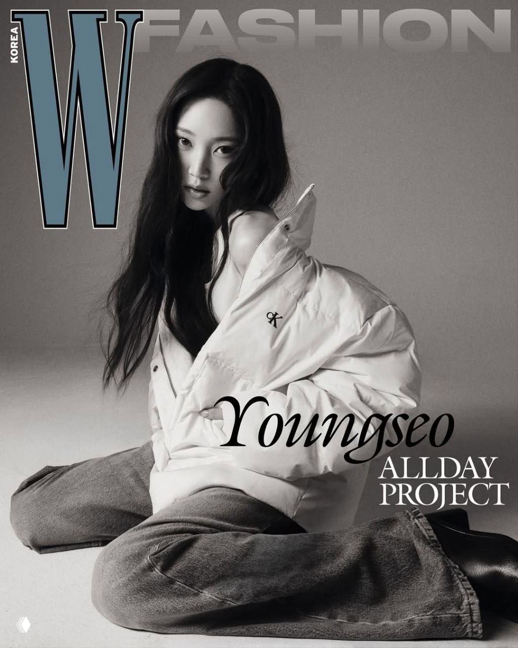 Чёрно‑белая студийная фотография: участница группы в объёмной куртке и джинсах, акцент на силуэте и логотипе бренда Calvin Klein