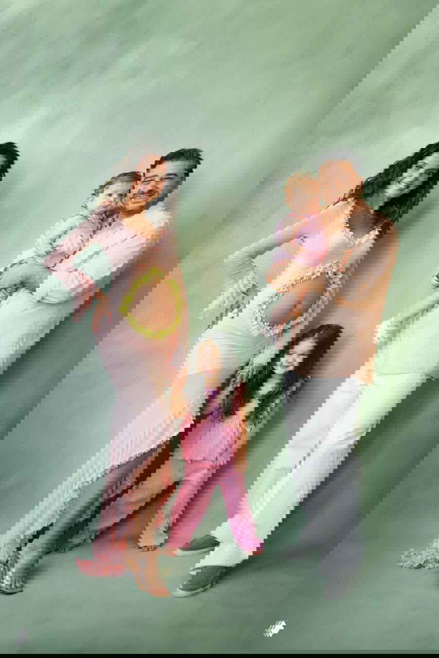 Полный рост семьи: Лиза Моряк с заметным животом в розовом, Сарик Андреасян с младшей дочкой на руках, и старшая дочь рядом.