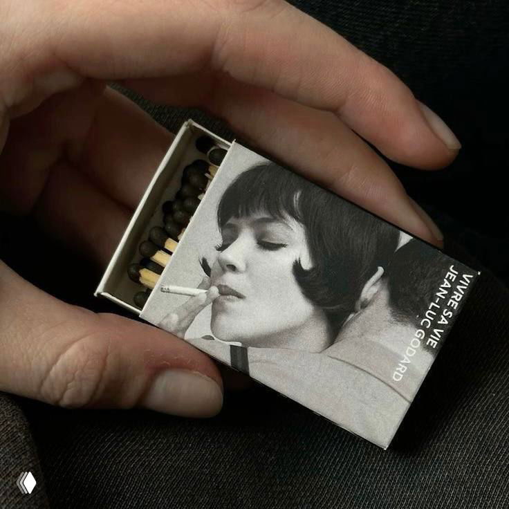 Рука держит спичечный коробок с чёрно‑белым винтажным изображением женщины, бытовая деталь добавляет интимности и ретро-настроения снимку.