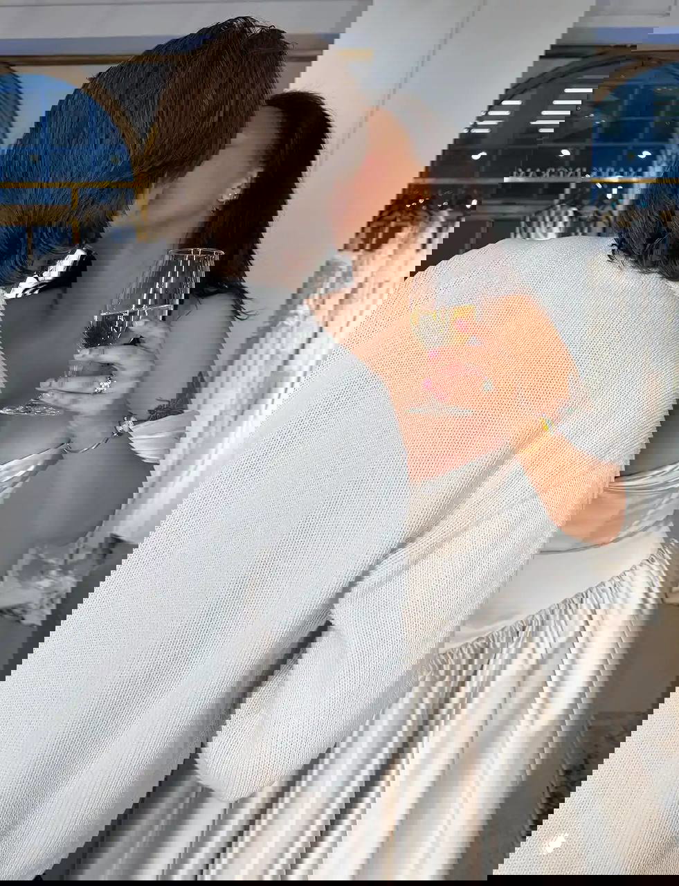 Невеста в ателье Mark Ingram целуется с гостем, держит бокал шампанского; видно сатиновое свадебное платье и гардероб салона на заднем плане.