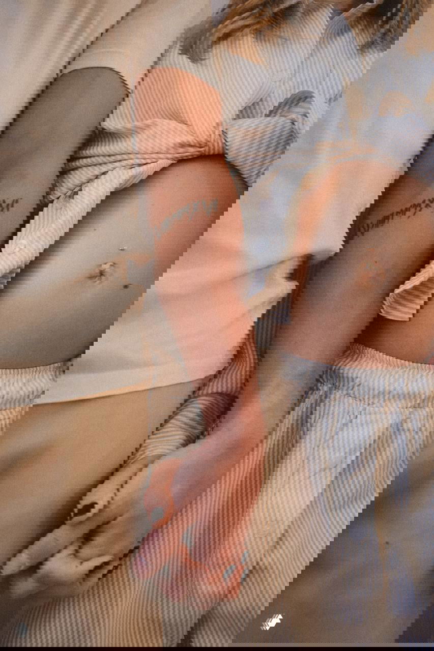 Крупный план рук пары: мужчина и женщина держатся за руки, рядом видна часть живота женщины и тату на мужской руке, кадр передаёт близость и поддержку.