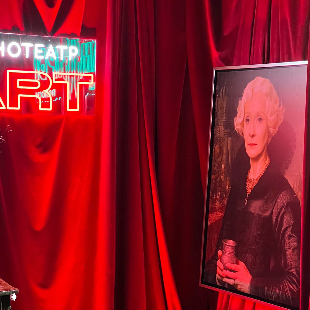 Красный драпированный фон с неоновым знаком и портретной картиной в раме — часть сценографии презентации сериала с викторианским мотивом.