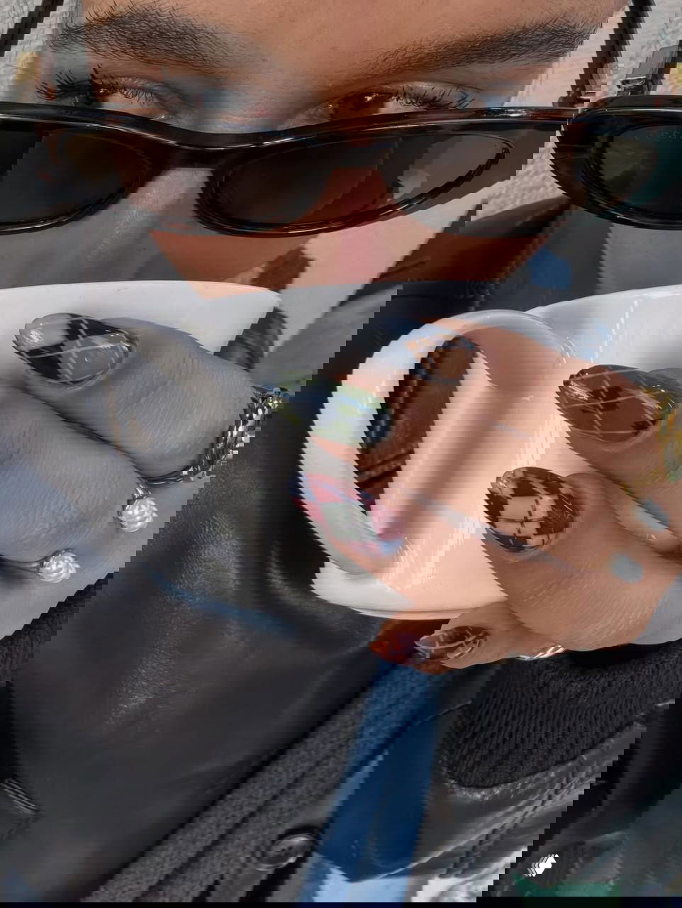 Крупный план рук с ромбовидным (argyle) дизайном в зелёно-синей и бордовой гамме; рука держит белую чашку.