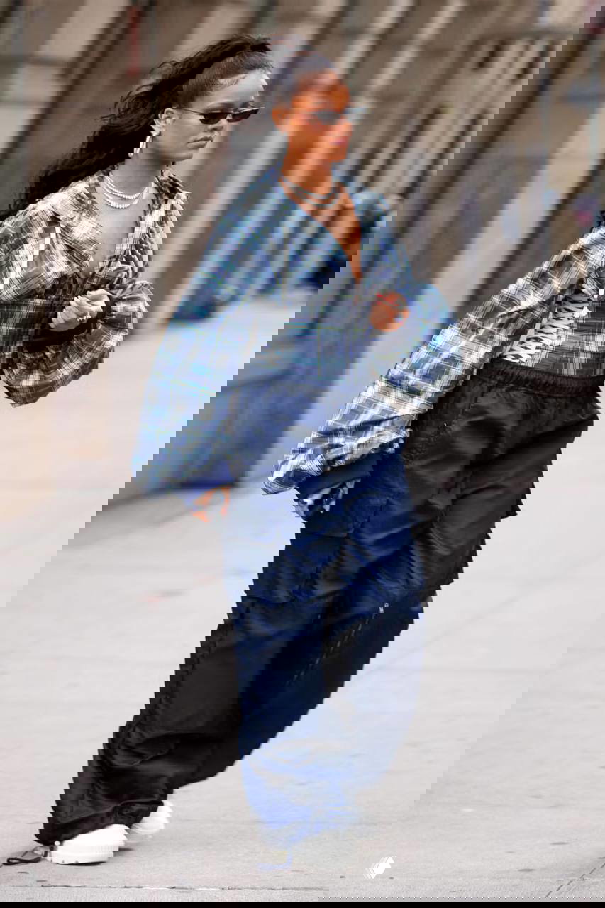 Стритстайл‑фото: объёмный клетчатый верх с корсетной шнуровкой и тёмные карго‑штаны, белые массивные кроссовки и аксессуары в непринуждённом лукe.