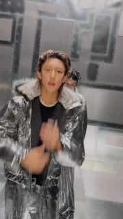 Солист в блестящей серебристой куртке в коридоре студии, динамичное слегка размытое фото из промо или репетиции, акцент на движении.