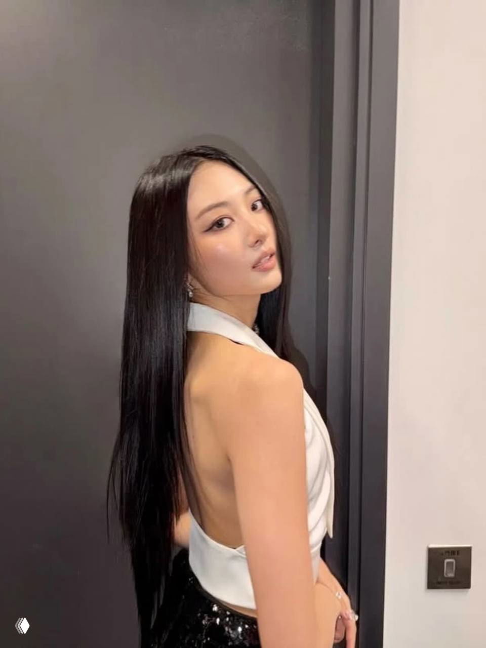 Молодая женщина в вечернем образе с длинными тёмными волосами; тонкая чёрная стрелка подчёркивает взгляд в кадре со студийным светом.