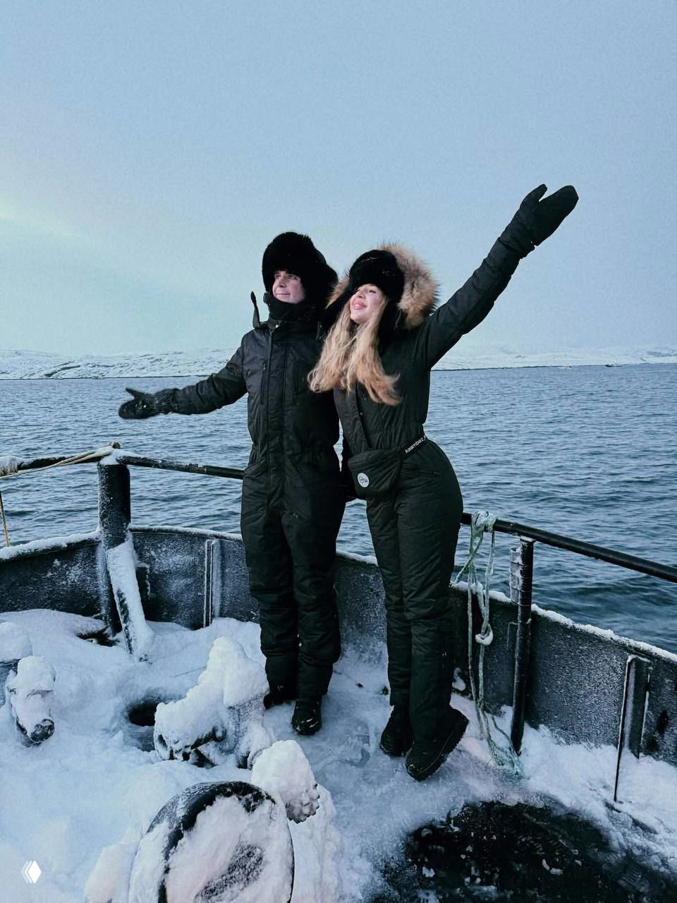 Аня и Артур на носу небольшого судна раскинули руки в боках над холодным морем; одежда утепленная, вокруг снежный лёд на палубе