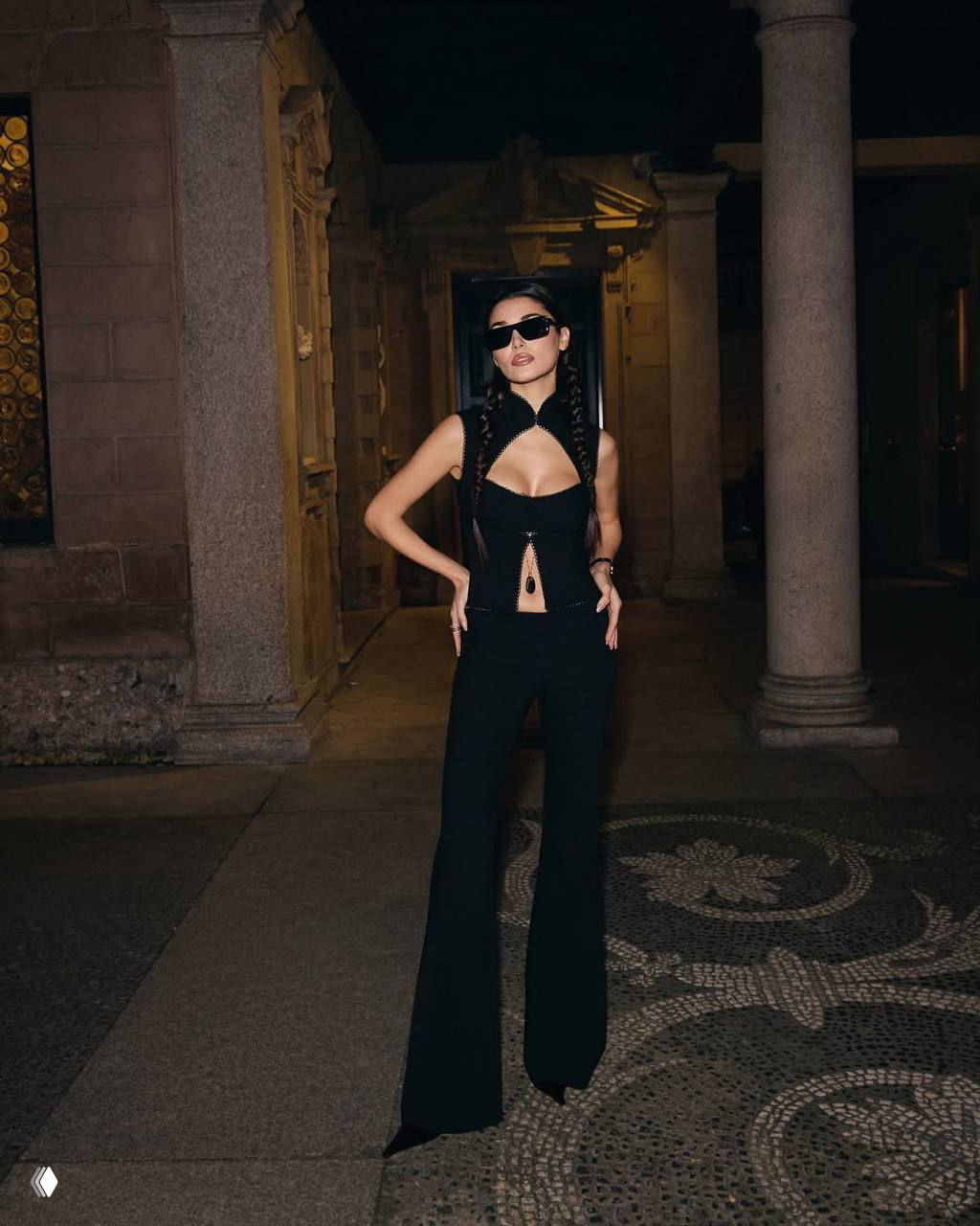 Портрет Ханде Эрчел в корсетном топе: крупный план показывает макияж, причёску и детали украшений на фоне колонн.