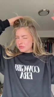 Кадр девушки в уютном свитшоте, расчёсывающей и улучшающей причёску руками, демонстрация текстуры волос и подготовки к простому образу.