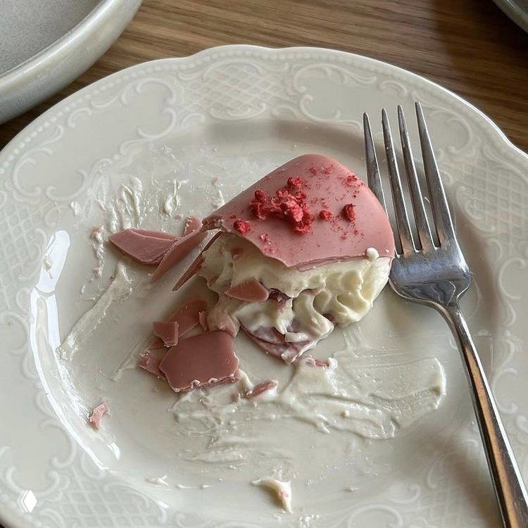 Остатки розового десерта на белой тарелке с вилкой — эстетический кадр со сладкой текстурой и приглушённой цветовой гаммой.