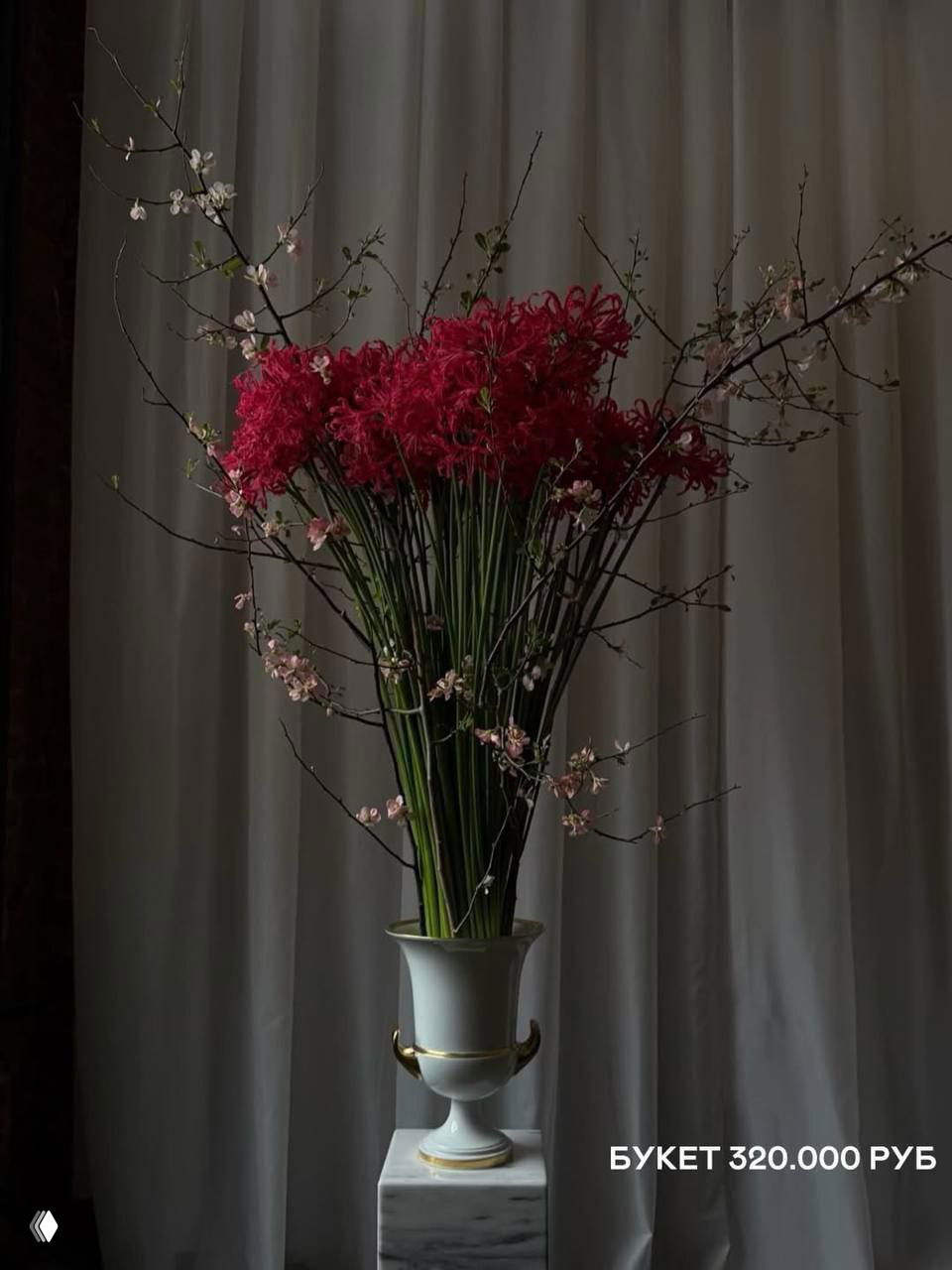 Высокая элегантная композиция с длинными зелёными стеблями и красными цветами в классической вазе на постаменте, драматичная студийная съёмка.